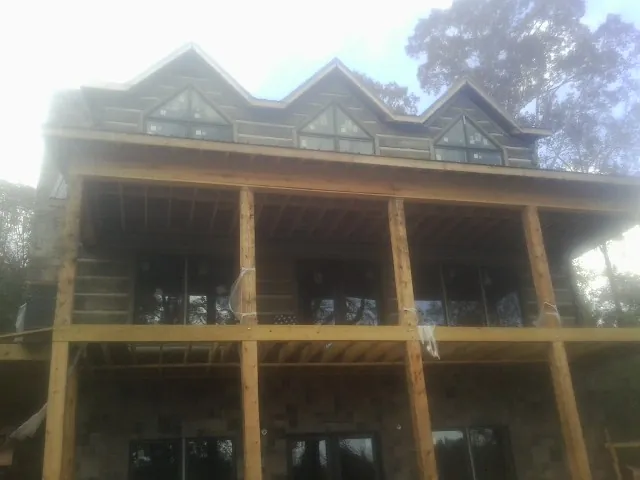 Dormers and porch framing on a large log home under construction — Roof Coating work by our crew in Blountstown