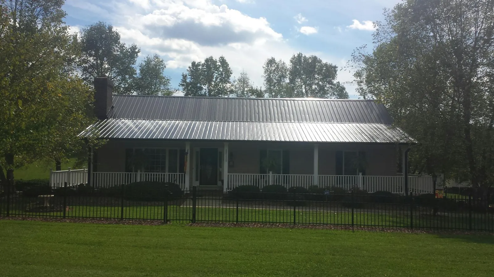 Gray metal roof on a brick ranch with a full width front porch — Gutter Guard Installation work by our crew in Blountstown