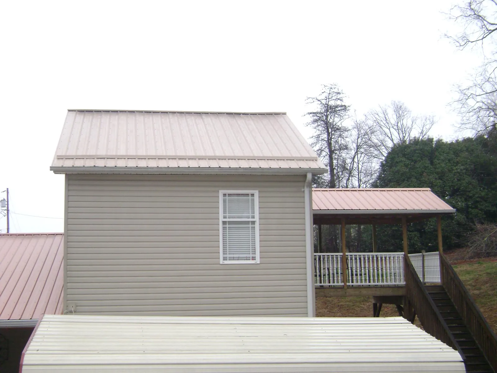 Tan metal roofs on a two story addition and attached porch, from a Roof Replacement job in Blountstown